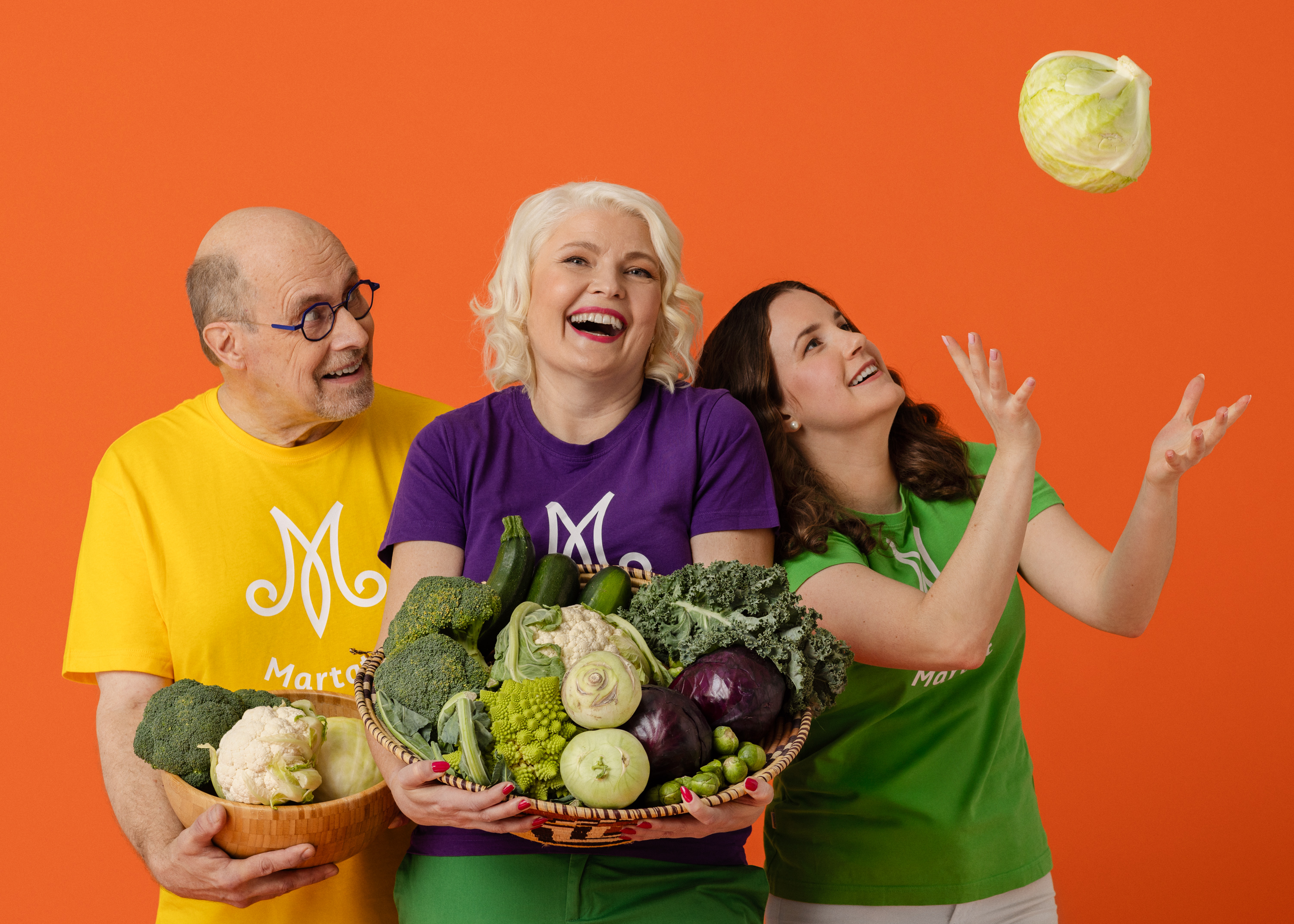 Kolme hymyilevää marttaa, joiden käsissä on tuoreita kasviksia.